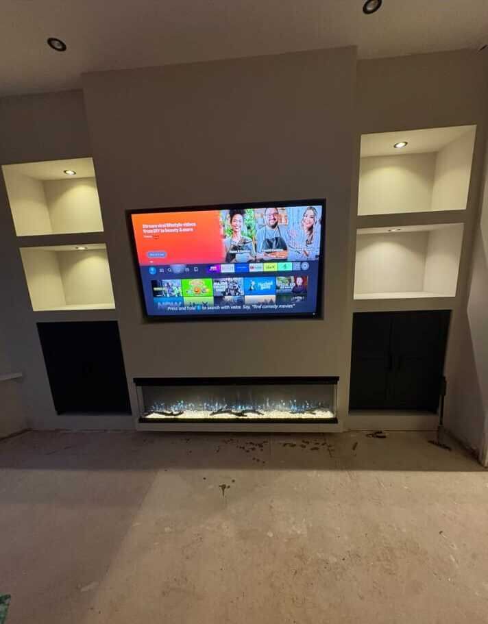 Media wall with illuminated alcove shelving and wall-mounted TV